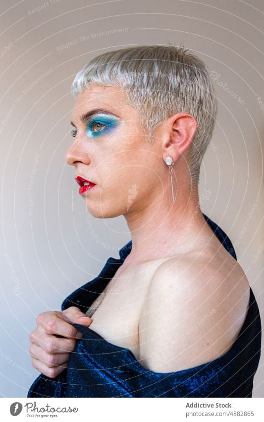 Porträt eines Transgender-Mannes mit Make-up Lidschatten schwul posierend queer Mode Individualität lgbtqi Nahaufnahme Stolz Studioaufnahme feminin rot