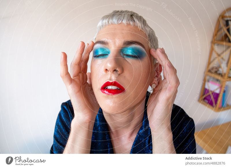 Porträt eines Transgender-Mannes mit Make-up Lidschatten schwul posierend queer Mode Individualität lgbtqi Nahaufnahme Stolz Studioaufnahme feminin rot