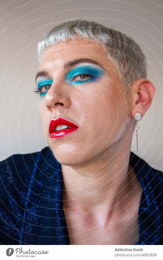 Porträt eines Transgender-Mannes mit Make-up Lidschatten schwul posierend queer Mode Individualität lgbtqi Nahaufnahme Stolz Studioaufnahme feminin rot