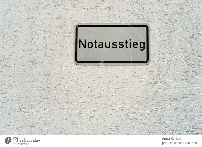 Ein Notausstieg Schild an einer weissen Aussenwand Fluchtweg Notausgang escape Wegweiser Ausweg Hinweisschild richtungsweisend Schilder & Markierungen