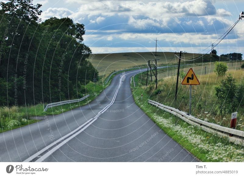 eine Kurve auf einer Landstraße in Polen Verkehrsschild Farbfoto Sommer Himmel Straße Menschenleer Verkehrswege Außenaufnahme Natur Landschaft Tag Wege & Pfade