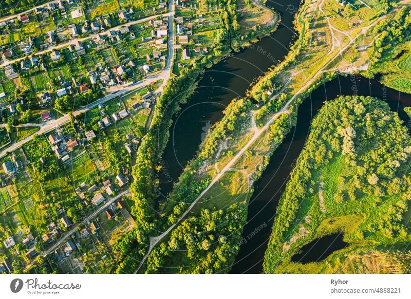 Luftaufnahme von ruhigen Fluss und Dorf in Belarus, Europa. Green Forest Woods Landschaft in sonnigen Sommerabend. Top View of Beautiful European Nature From High Attitude. Drone Ansicht. Vogelperspektive Ansicht