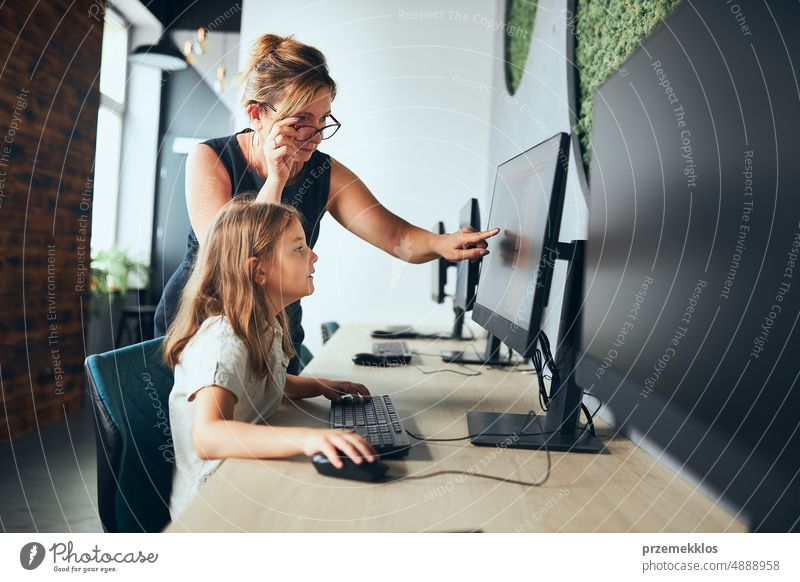 Computerunterricht in der Schule. Lehrer unterstützt Schülerin beim Unterricht in der Grundschule. Kind lernt Computer auf elementaren Informatikunterricht. Zurück zur Schule