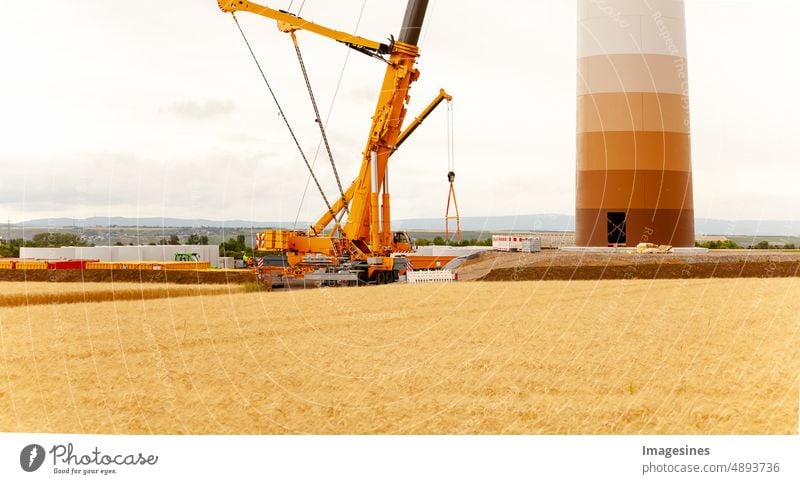 Bau und Montage einer Windkraftanlage per Kran auf einer Baustelle. Bauarbeiten am Windpark in Deutschland. Energiesparkonzept aus dem Bau von Windkraftanlagen mit Abendhimmel