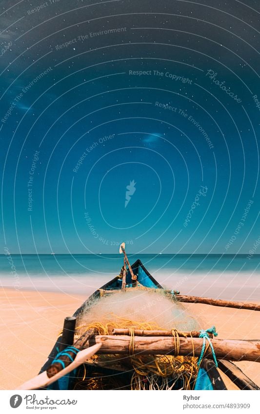 Goa, Indien. Real Night Sky Sterne. Natürliche Starry Sky Blue Color Above Sea Seascape Ocean Beach. Hintergrund. Geparktes altes Holzboot an der Küste 2020