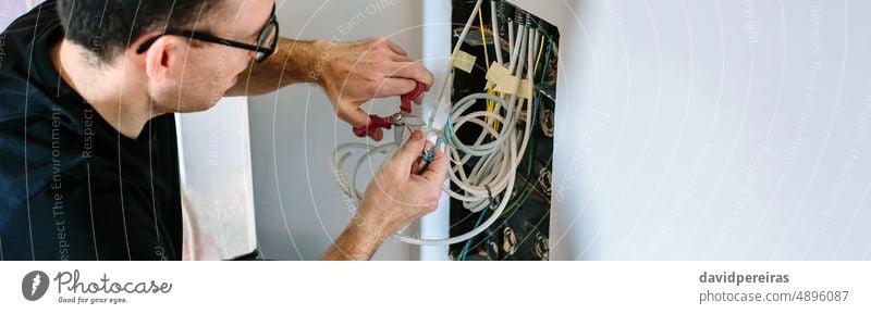 Techniker schneidet Kabel für die Installation einer Telekommunikationsbox Installateur Transparente Netz Kopfball Panorama panoramisch Schneiden Mann Schere