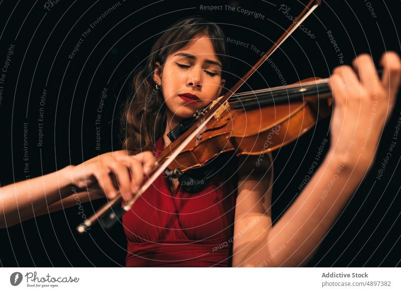 Musikerin spielt Geige auf der Bühne Frau spielen Konzert Schauplatz ausführen Theater dunkel Augen geschlossen Instrument Klang Melodie unterhalten üben