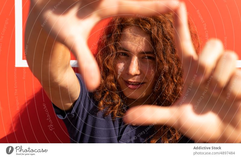 Porträt einer gestikulierenden Frau in Diamantform Lächeln Form Sonnenlicht Rotschopf lockig Behaarung schön Lifestyle Selbstvertrauen cool Hand Freizeit