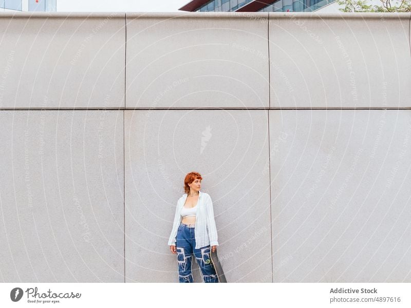 Frau mit Skateboard an der Wand Skateboarderin Hobby sportlich Zeitvertreib Freizeit Straße urban Aktivität genießen anhaben lässig Gebäude attraktiv Sommerzeit