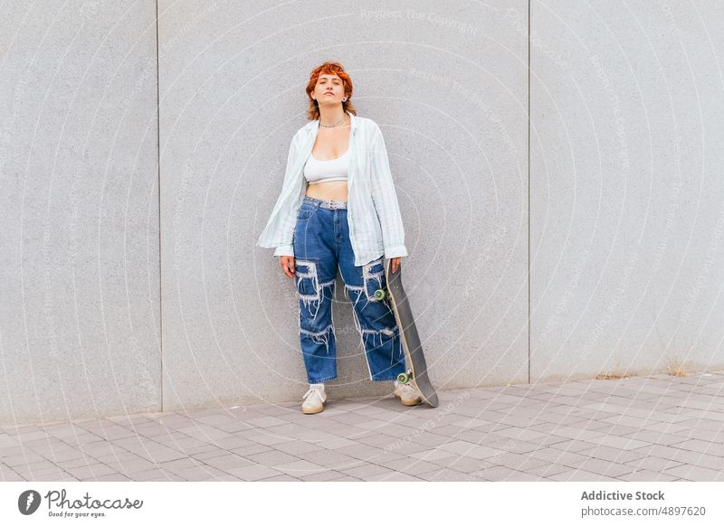 Frau mit Skateboard an der Wand Skateboarderin Hobby sportlich Zeitvertreib Freizeit Straße urban Aktivität genießen anhaben lässig Gebäude attraktiv Sommerzeit