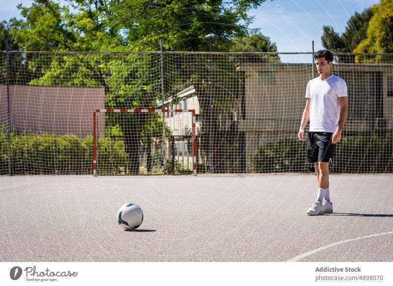 Männlicher Fußballspieler betrachtet den Ball während des Trainings männlich Blick praktizieren Gericht Athlet Selbstvertrauen Netz ernst Tatkraft Spielen Sport