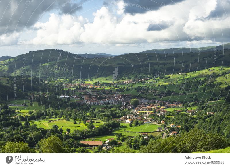 Kleine, von Hügeln umgebene Siedlung Wohnsiedlung Dorf Gebäude Landschaft Hügelseite wohnbedingt Haus Feld wolkig Valles Pasiegos Kantabrien Spanien Sommer