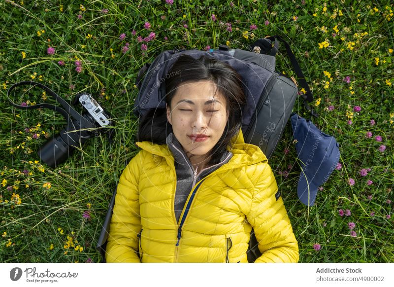 Porträt eines schönen asiatischen Mädchens, das auf dem Gras liegt und die Hand hält Chinesisches Mädchen Spanien aktiv Rucksack Windstille Fotokamera