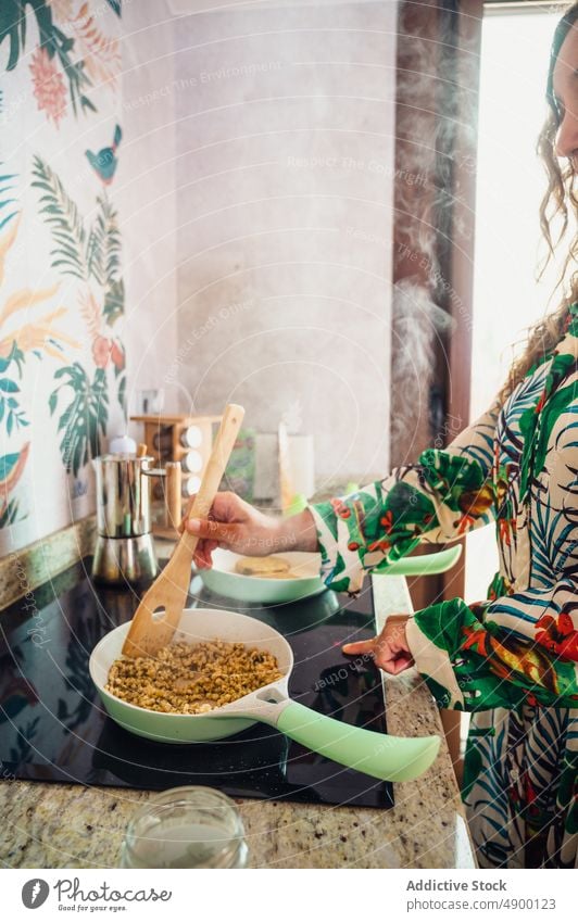 Unbekannte Frau brät Quinoa auf dem Herd braten Küche kulinarisch selbstgemacht Speise Koch Mahlzeit Spachtel rühren lecker vorbereiten heimwärts Rezept