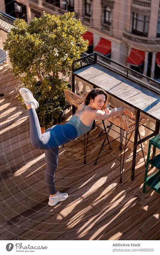 Fitte Frau beim Sport auf der Terrasse Sportlerin Übung Training Gesunder Lebensstil üben Hobby Straße sportlich Bein angehoben Ausdauer Herausforderung Kraft