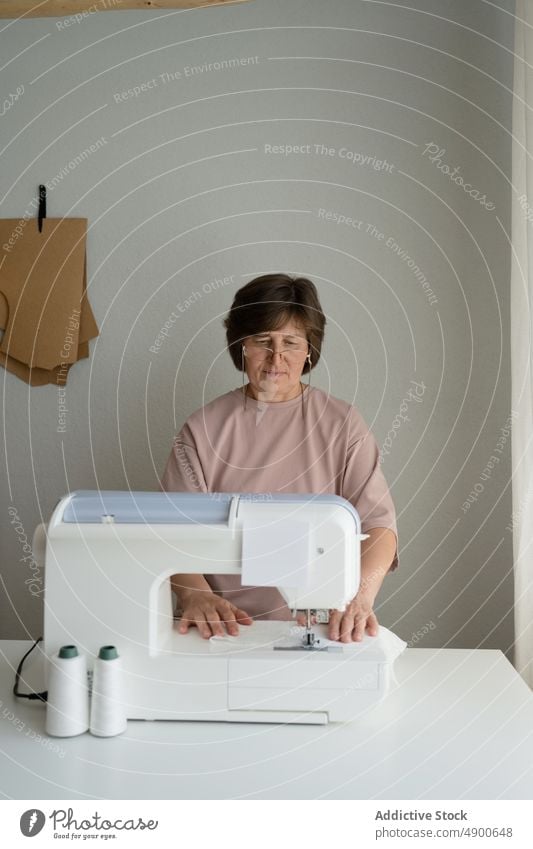 Schneiderin beim Nähen an der Maschine im Atelier Näherin Damenschneiderin Nähmaschine nähen Gewebe Textil Arbeit Werkstatt Herstellung Vorrichtung Werkzeug