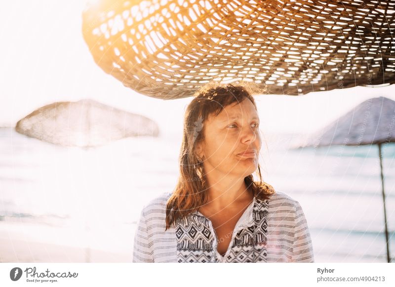 Erwachsene kaukasische Frau entspannt posiert unter Strand Sonnenschirm auf Sonnenuntergang. Urlaub am Meer Ozean Erwachsener attraktiv authentisch schön