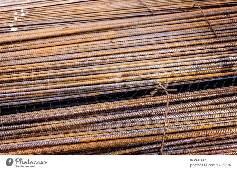 Zusammengebundene rostende Metallstäbe im Sonnenlicht, diagonal Stäbe Baustelle Rost farbig Eisen gewunden Hintergrund Menge Struktur Bewehrungseisen Bund