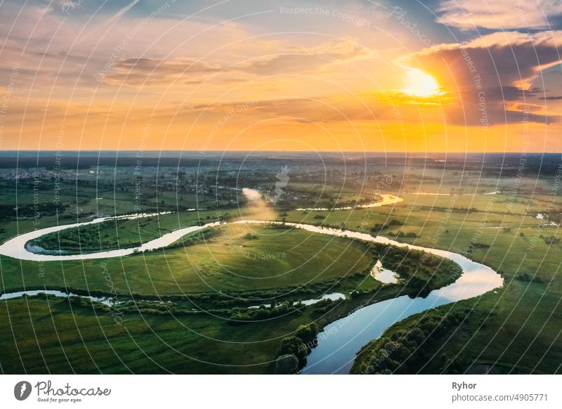 Luftaufnahme. Schöne Sonnenuntergang Sonnenschein über grünen Wald, Wiese und Flusslandschaft in sonnigen Abend. Top View of European Nature From High Attitude In Summer Sunrise. Vogelperspektive Ansicht. Weißrussland.