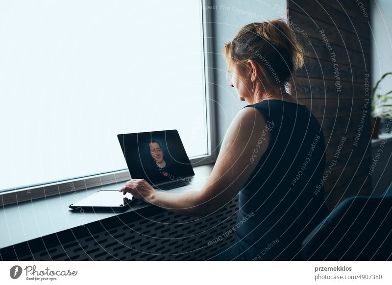 Geschäftsfrau mit Business-Videoanruf auf Laptop im Büro. Reife, vielbeschäftigte Frau, die aus der Ferne vom Büro aus arbeitet. Weiblicher Manager mit digitalen Geräten. Fernkommunikation. Videoanruf. Fernarbeit