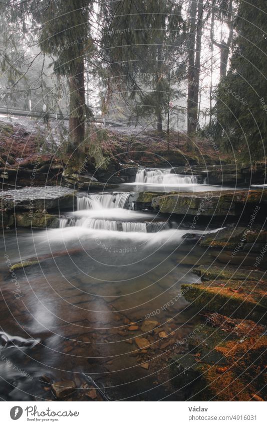 Klares Wasser, fotografiert mit langer Belichtungszeit durch fließende, moosbewachsene Felsen mit herbstlichen Blattfarben. Krasna, Beskiden, Tschechische Republik, Herz von Europa