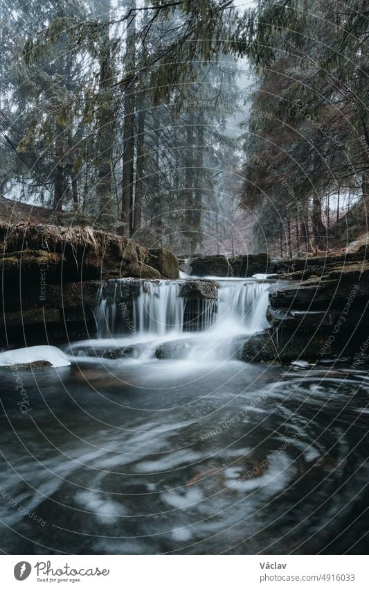 Klares Wasser, fotografiert mit langer Belichtungszeit durch fließende, moosbewachsene Felsen mit herbstlichen Blattfarben. Krasna, Beskiden, Tschechische Republik, Herz von Europa