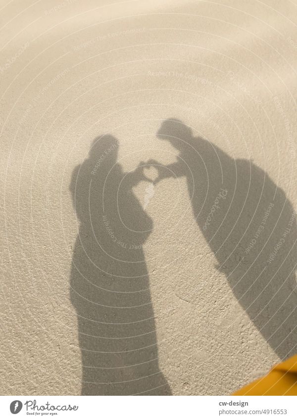 Verliebtes Pärchen am Strand zeigt ein Herz Paar Sand Außenaufnahme Ferien & Urlaub & Reisen Küste Wasser Zusammensein Farbfoto pärchen Erholung Natur Sommer