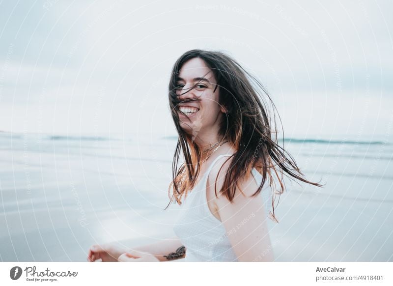 Junge Frau, die an einem paradiesischen Strand läuft, während sie sich umdreht und sorglos in die Kamera lächelt. Freiheit, Freiheit und Straße reisen Konzept. Gen Z modernes Leben, soziales Netzwerk, Erfahrungen teilen