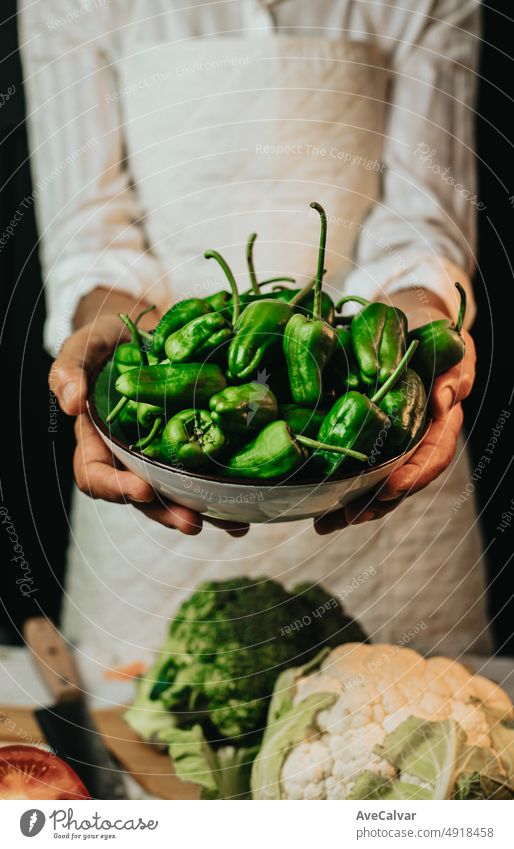 Close up Bild einer alten Frau Kochen Koch packt Paprika von Padron und zeigt in die Kamera, bevor sie in einem gesunden food.Rustic Küche Kochen von Chef gemacht.