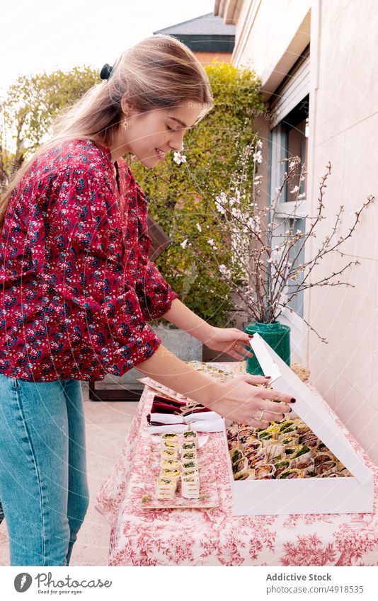 Zufriedene Frau serviert Tortilla-Rollen auf dem Tisch dienen rollen Snack Lebensmittel Amuse-Gueule Terrasse Festessen Speise geschmackvoll lecker appetitlich