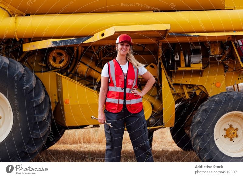 Positive Frau mit Schraubenschlüssel bei Mähdrescher Erntemaschine Arbeiter Instrument Landwirt Ackerbau Landschaft Feld Werkzeug Vorrat Mechaniker Techniker