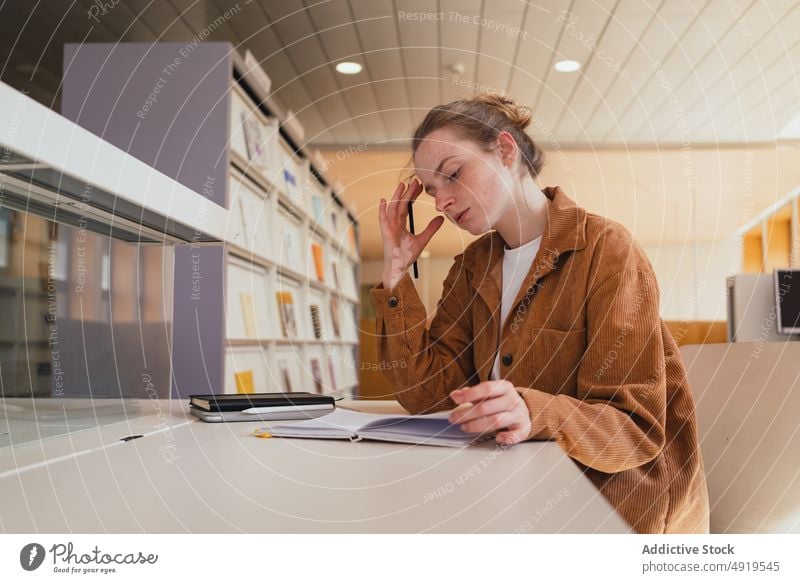 Studentin macht Notizen in der Bibliothek Frau Schüler schreiben Hinweis lernen Universität Anweisung Hausaufgabe Bildung jung Tastkopf Planer Notebook lässig