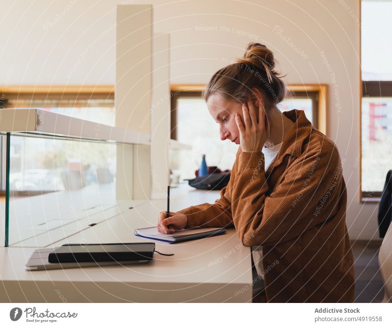 Studentin macht Notizen in der Bibliothek Frau Schüler schreiben Hinweis lernen Universität Anweisung Hausaufgabe Bildung jung Tastkopf Planer Notebook lässig