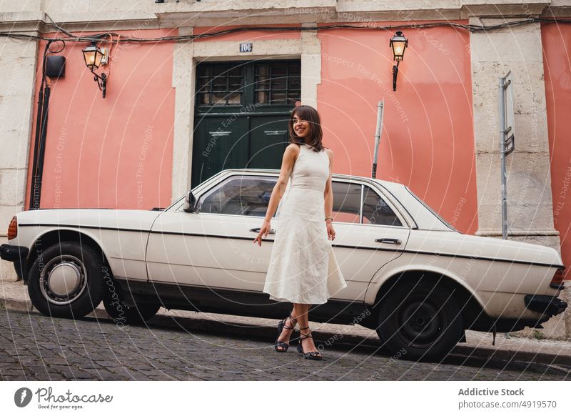 Zufriedene Frau bei Retro-Auto in der Stadt Straße PKW Großstadt Stil Oldtimer retro altehrwürdig Kleid geparkt Gebäude Kleidung positiv froh angenehm Optimist