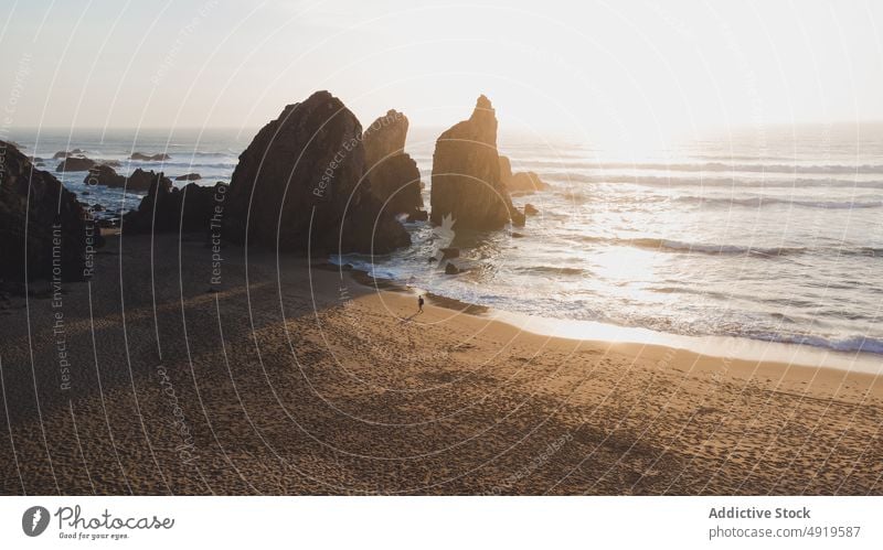 Küste am Meer mit Klippen bei Sonnenuntergang Person Spaziergang MEER Felsen Strand Wasser Ufer Natur Insel tropisch Abend Sommerzeit Sonnenlicht Sand Resort