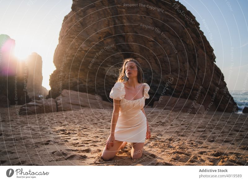 Frau sitzend am Strand mit Felsen Reisender MEER Wasser Ufer Sonnenuntergang Zeitvertreib sensibel Fernweh Stein feminin Kleid genießen Anmut Ausflug ruhen