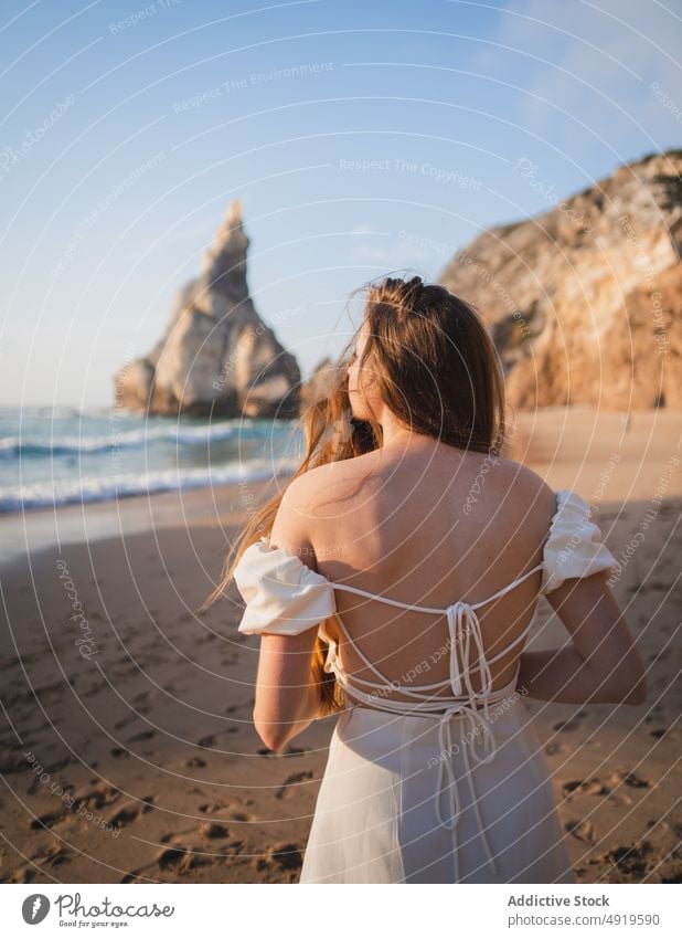 Frau am Strand stehend mit Felsen Reisender MEER Wasser Ufer Sonnenuntergang Zeitvertreib sensibel Fernweh Stein feminin Kleid genießen Anmut Ausflug ruhen