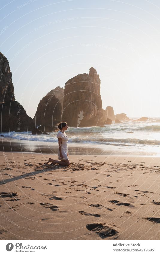 Frau sitzt am wogenden Meer Reisender MEER Strand Wasser Ufer Sonnenuntergang Zeitvertreib Ausflug ruhen Sonnenlicht Erholung winken reisen Klippe Felsen