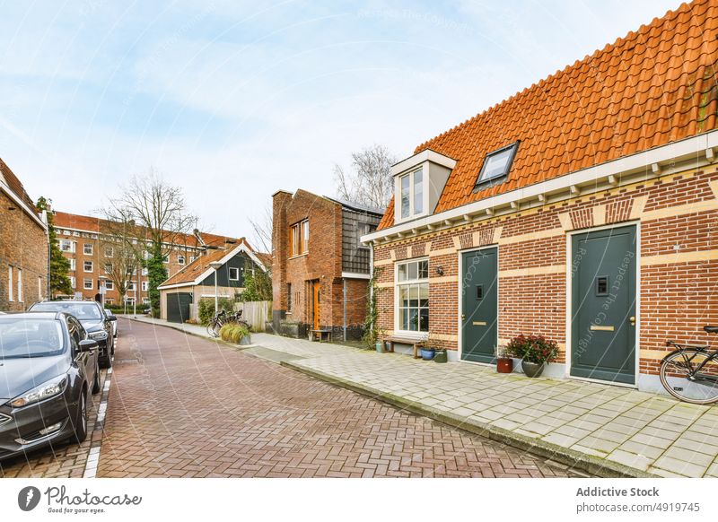 Straße mit aufgereihten Häusern neben geparkten Autos Bürgersteig PKW Haus Architektur Großstadt Straßenbelag Stadt Tag urban im Freien Stadtbild Baum