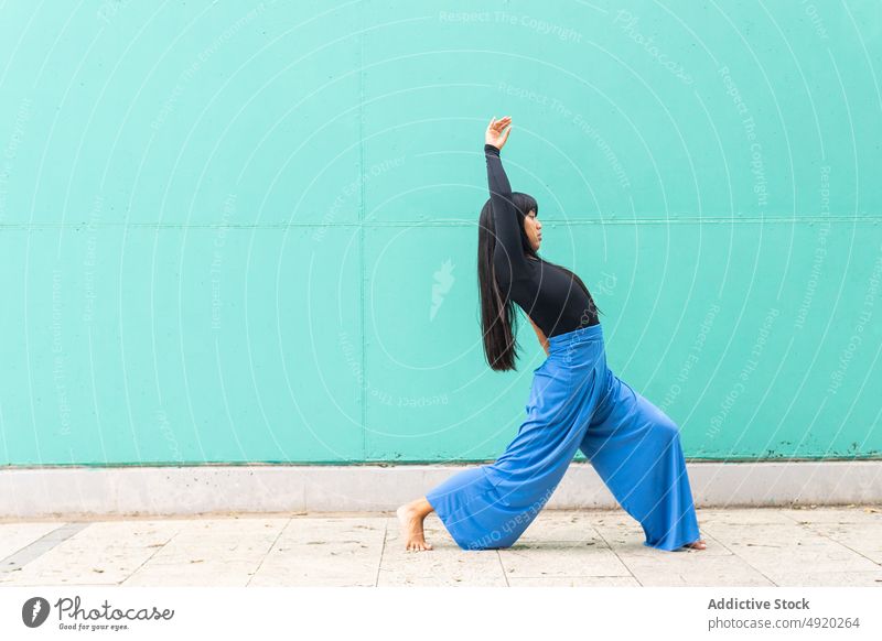 Asiatische Frau tanzt auf dem Bürgersteig Tanzen Straße Straßenbelag Anmut Wand Arm angehoben Ausfallschritt urban jung asiatisch ethnisch Energie Talent Barfuß