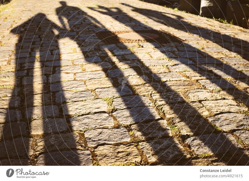 Schatten von vier Personen im Abendlicht Licht Außenaufnahme Haus Abendstimmung Bauwerk Sonnenlicht gelb Farbfoto Abenddämmerung Straße Street Sonnenuntergang