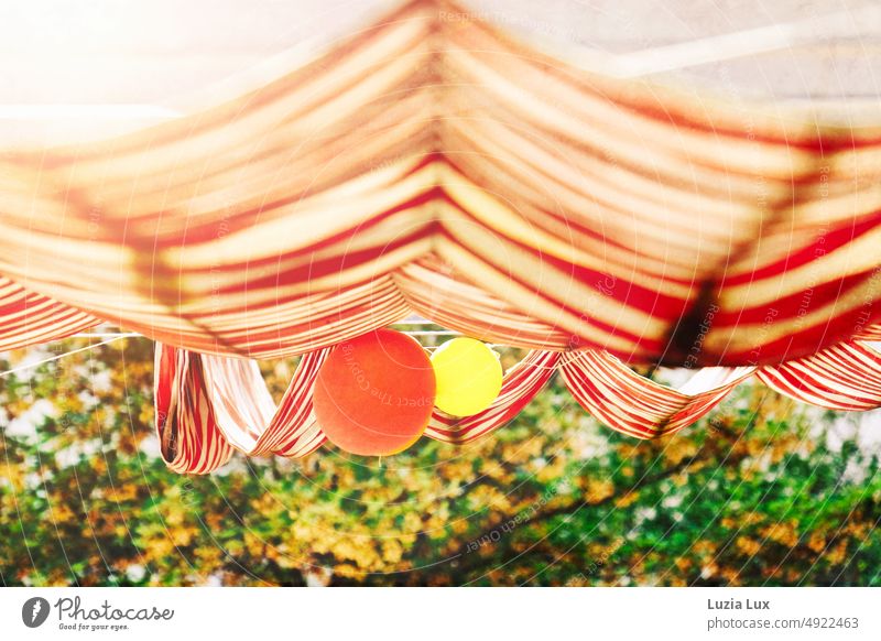 Blick aus dem Fenster ins Grüne, auf eine rotweingestreifte Markise und Luftballons rot und gelb weiss rotweiß gestreift Licht sommerlich Streifen