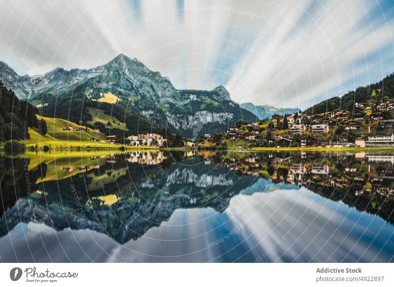 Malerische Landschaft mit ruhigem See, in dem sich Berge und Häuser spiegeln Berge u. Gebirge Natur Dorf Cottage Tal malerisch Hochland Wohnsiedlung