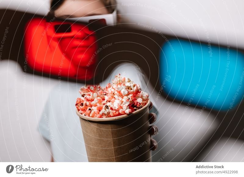 Durch rote Linse Blick auf Mädchen mit Popcorn Kind 3d Brille Vergnügen Popkorn Snack unterhalten Leckerbissen Hobby froh Optimist positiv Kino Lebensmittel