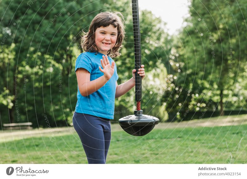 Mädchen winkt Hand in der Nähe Schaukel pendeln Seil Wellenhand Spielplatz Park Sommer Lächeln ruhen Gruß Wochenende Kind wenig Kindheit Glück lässig froh