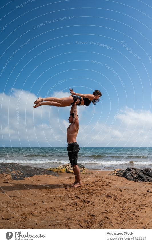 Paar macht Acro Yoga gegen bewölkten Himmel Akro-Yoga Strand Zusammensein Arme hochgezogen MEER Gleichgewicht Sommer üben Asana Mann Frau Energie Wochenende