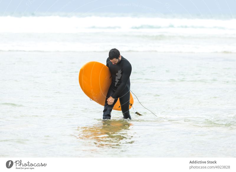 Männlicher Surfer, der vor dem Reiten einer Welle ins Meer geht Mann Surfbrett Spaziergang Sport sportlich Feiertag genießen Gesundheit Zeit verbringen jung