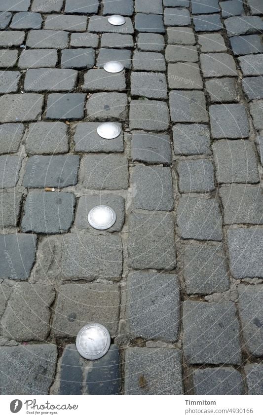 Der Fährtenleser ist recht sicher: hier war jemand! Platz Pflastersteine Kopfsteinpflaster Stein Markierung Metall Linie Fugen trocken Menschenleer