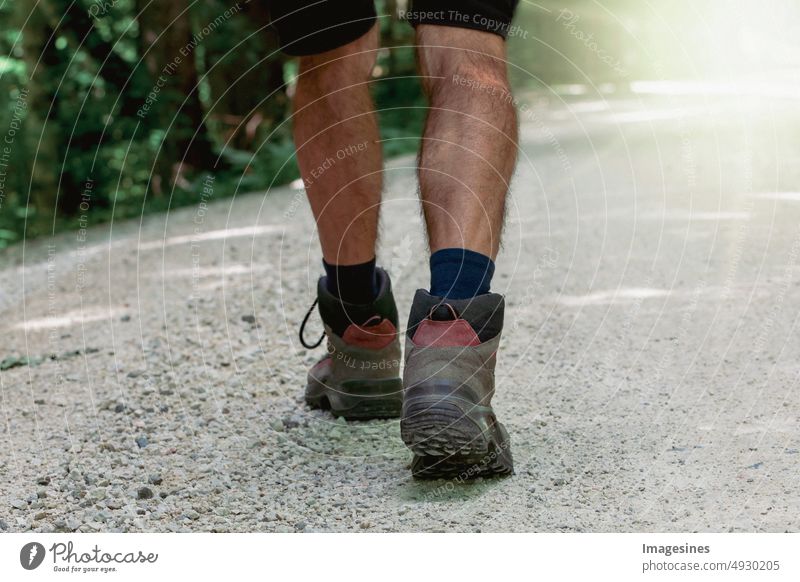 Wandern. Beine einer Person. Ein Wanderschuh. Tagsüber auf einem Pfad im Wald spazieren gehen. allein auf der rauen Schotterstraße zu Fuß. Gehen Straße wandern