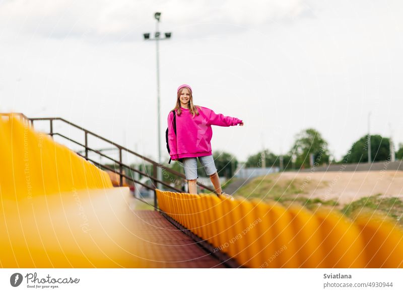 Ein junges Mädchen mit einem Rucksack läuft durch die Tribüne des Schulstadions Schule Schüler Teenager Schulzeit Bildung Frau Porträt Stadion Hintergrund